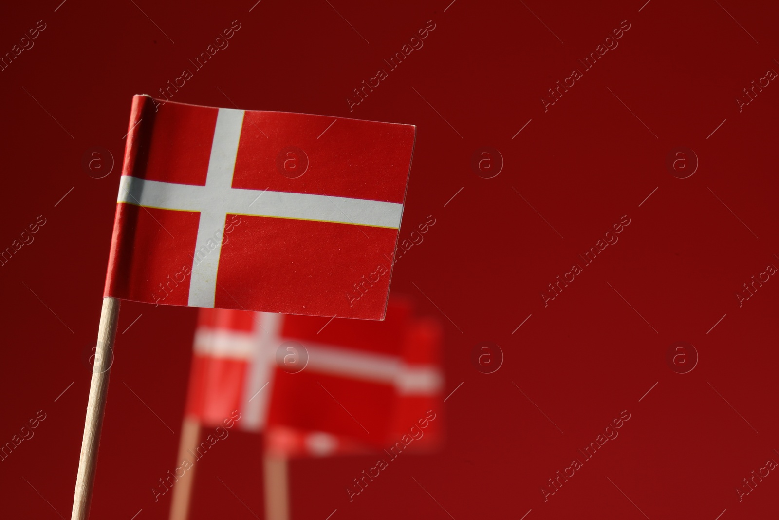 Photo of Small paper flags of Denmark on red background, selective focus. Space for text