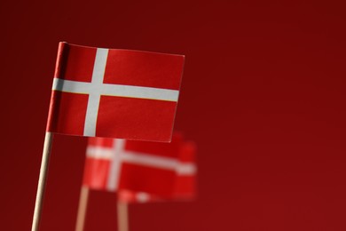 Photo of Small paper flags of Denmark on red background, selective focus. Space for text