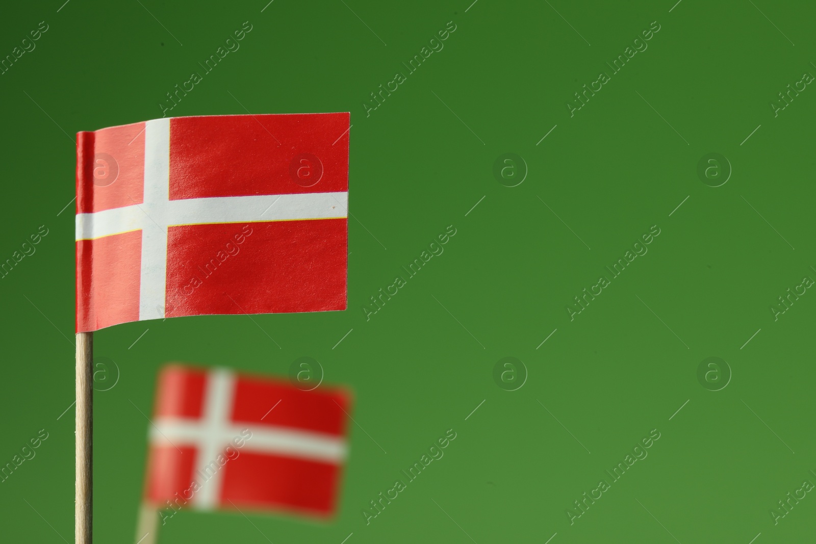 Photo of Small paper flags of Denmark on green background, selective focus. Space for text