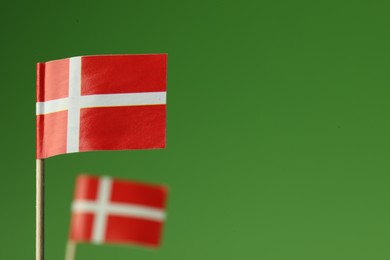 Photo of Small paper flags of Denmark on green background, selective focus. Space for text