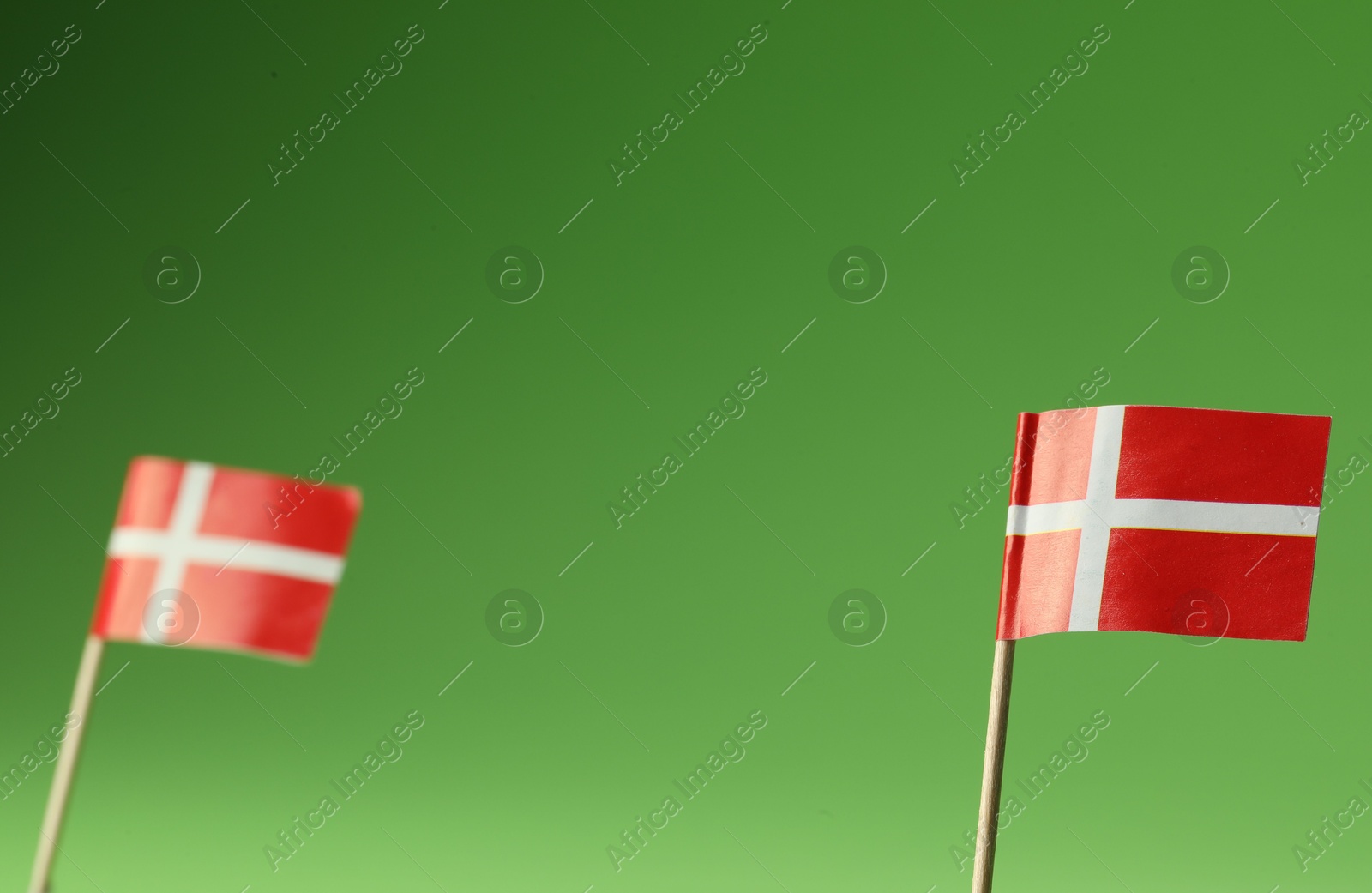 Photo of Small paper flags of Denmark on green background, selective focus. Space for text