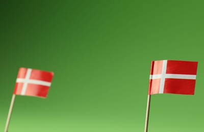 Small paper flags of Denmark on green background, selective focus. Space for text