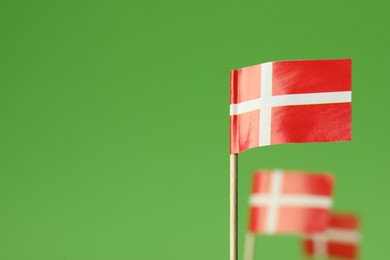 Photo of Small paper flags of Denmark on green background, selective focus. Space for text