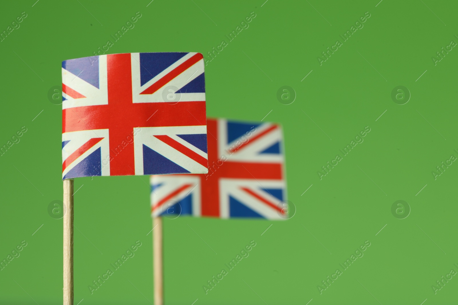 Photo of Small paper flags of United Kingdom on green background, selective focus. Space for text