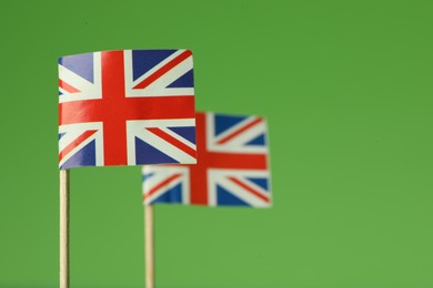 Photo of Small paper flags of United Kingdom on green background, selective focus. Space for text