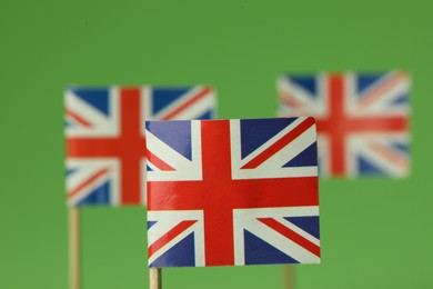 Photo of Small paper flags of United Kingdom on green background, selective focus