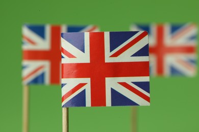 Photo of Small paper flags of United Kingdom on green background, selective focus