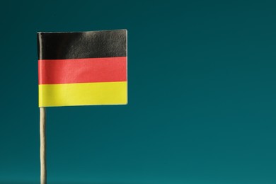 Small paper flag of Germany on teal background, closeup. Space for text