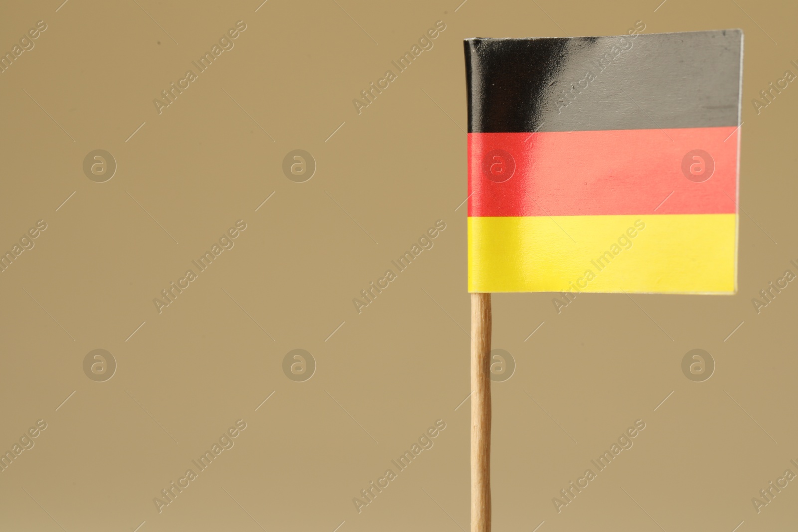 Photo of Small paper flag of Germany on beige background, closeup. Space for text