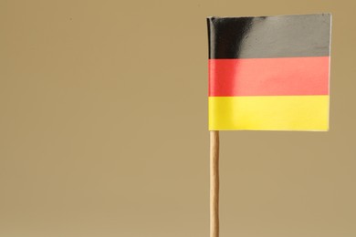 Photo of Small paper flag of Germany on beige background, closeup. Space for text