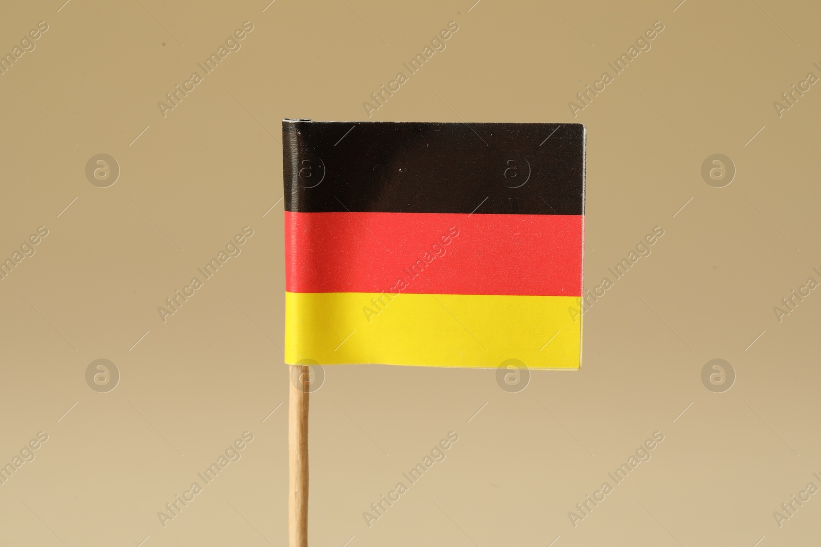 Photo of Small paper flag of Germany on beige background, closeup