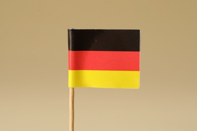 Small paper flag of Germany on beige background, closeup