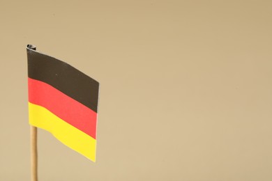 Photo of Small paper flag of Germany on beige background, closeup. Space for text