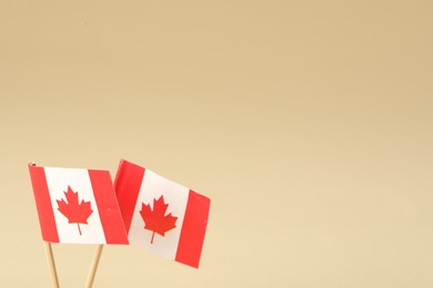 Small paper flags of Canada on beige background. Space for text