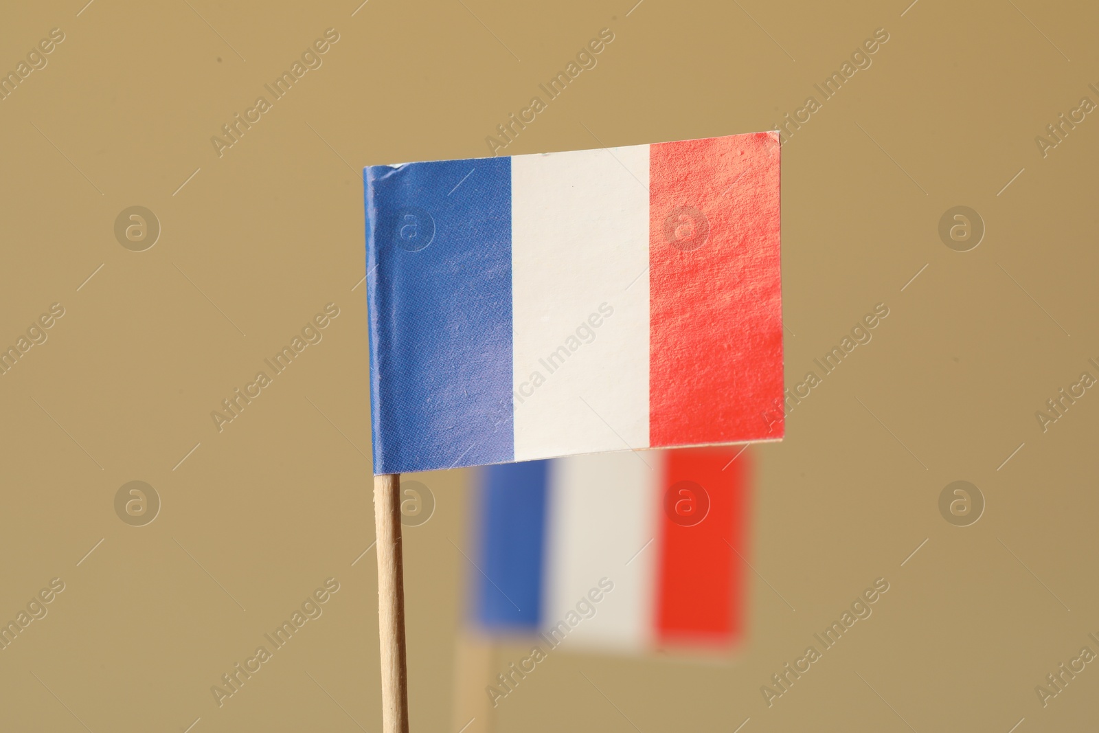 Photo of Small paper flags of France on beige background, selective focus