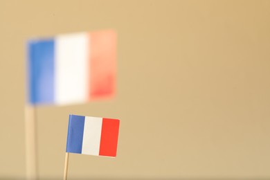 Photo of Small paper flags of France on beige background, selective focus. Space for text