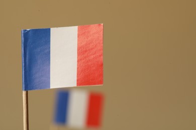 Small paper flags of France on beige background, selective focus. Space for text