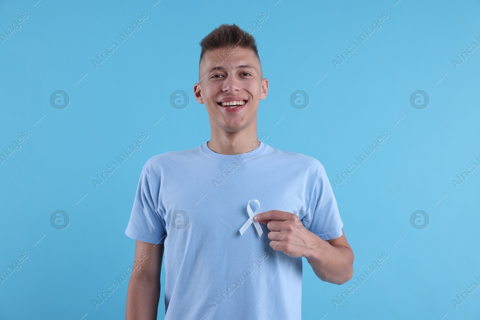 Photo of Prostate cancer awareness. Man with light blue ribbon as symbol of support on color background