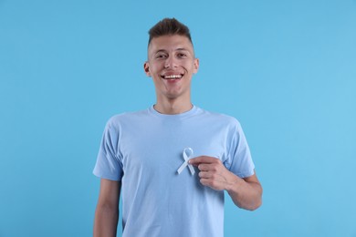 Prostate cancer awareness. Man with light blue ribbon as symbol of support on color background