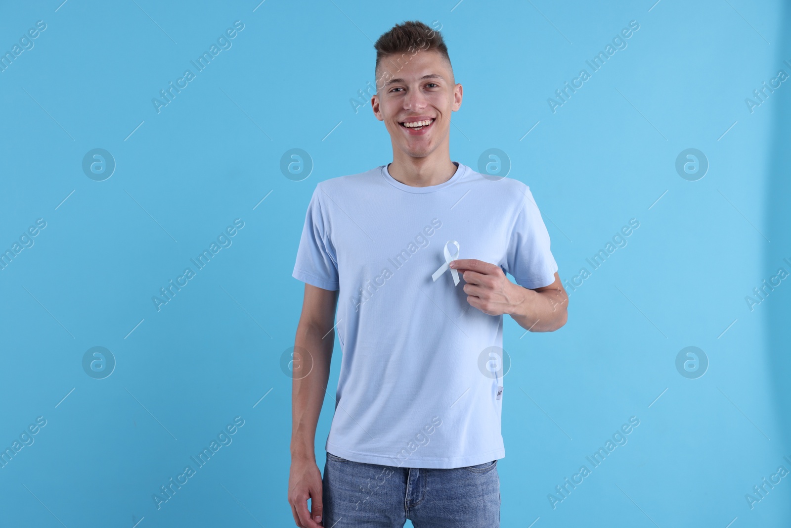 Photo of Prostate cancer awareness. Man with light blue ribbon as symbol of support on color background