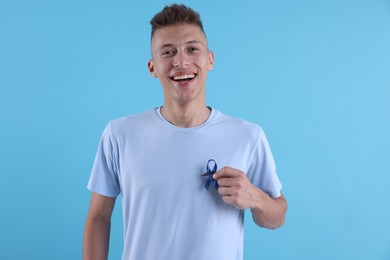Photo of Prostate cancer awareness. Man with blue ribbon and fake mustache on color background
