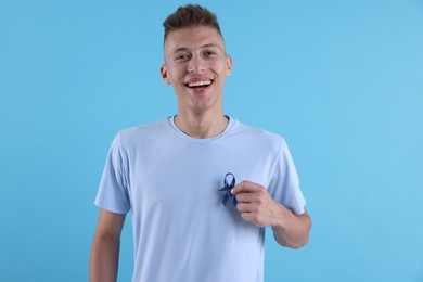 Prostate cancer awareness. Man with blue ribbon and fake mustache on color background