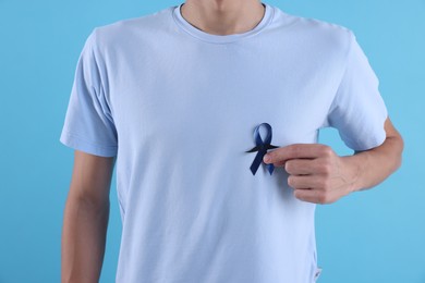 Photo of Prostate cancer awareness. Man with blue ribbon and fake mustache on color background, closeup