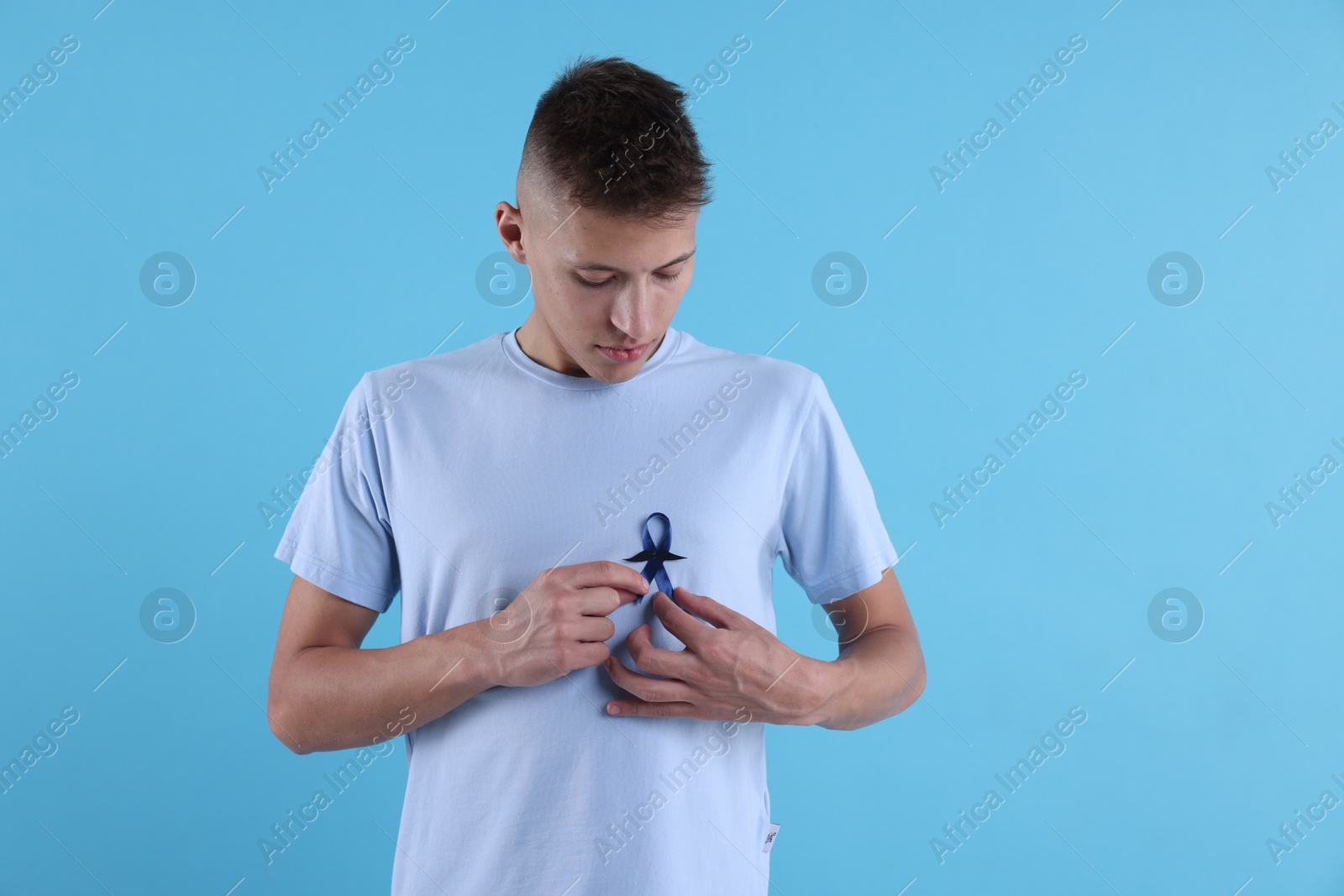 Photo of Prostate cancer awareness. Man with blue ribbon and fake mustache on color background