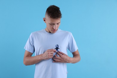 Photo of Prostate cancer awareness. Man with blue ribbon and fake mustache on color background