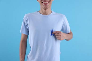 Photo of Prostate cancer awareness. Man with blue ribbon as symbol of support on color background, closeup