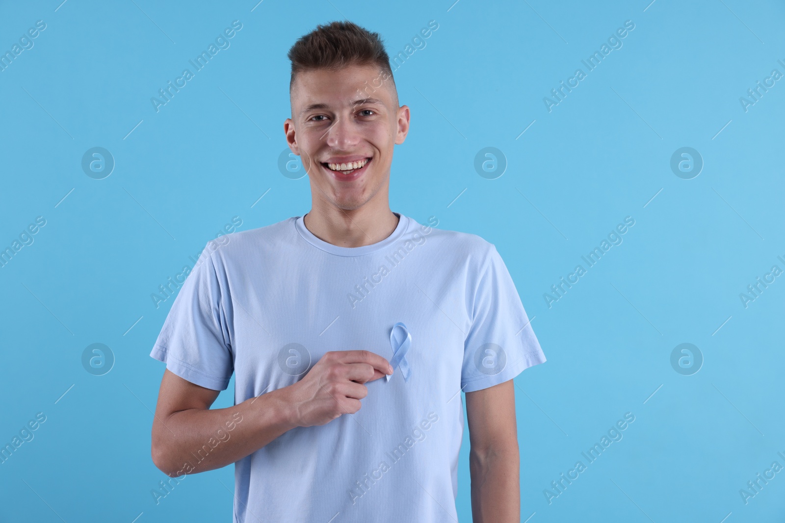 Photo of Prostate cancer awareness. Man with light blue ribbon as symbol of support on color background