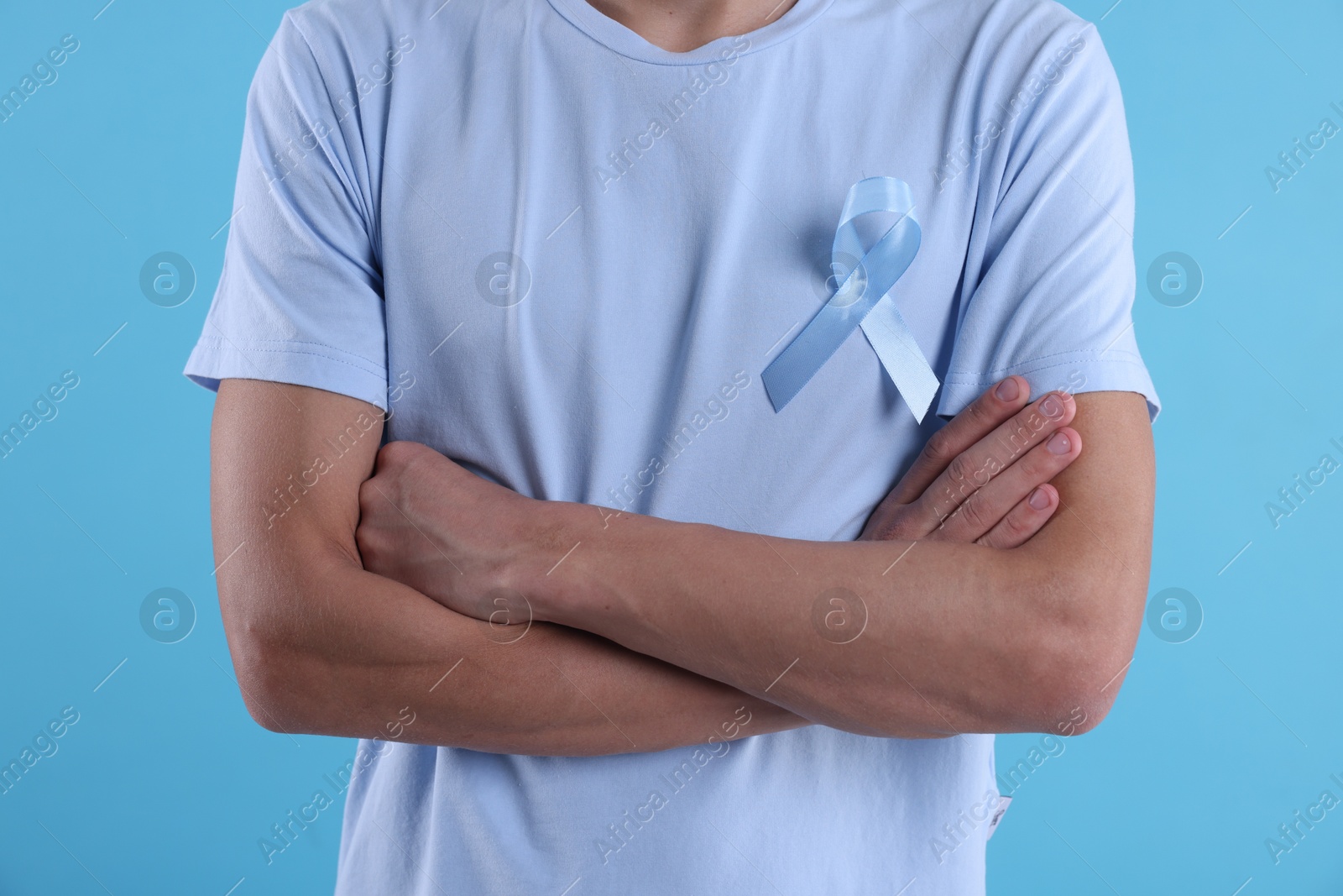 Photo of Prostate cancer awareness. Man with light blue ribbon as symbol of support on color background, closeup