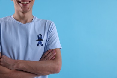 Prostate cancer awareness. Man with blue ribbon and fake mustache on color background, closeup. Space for text