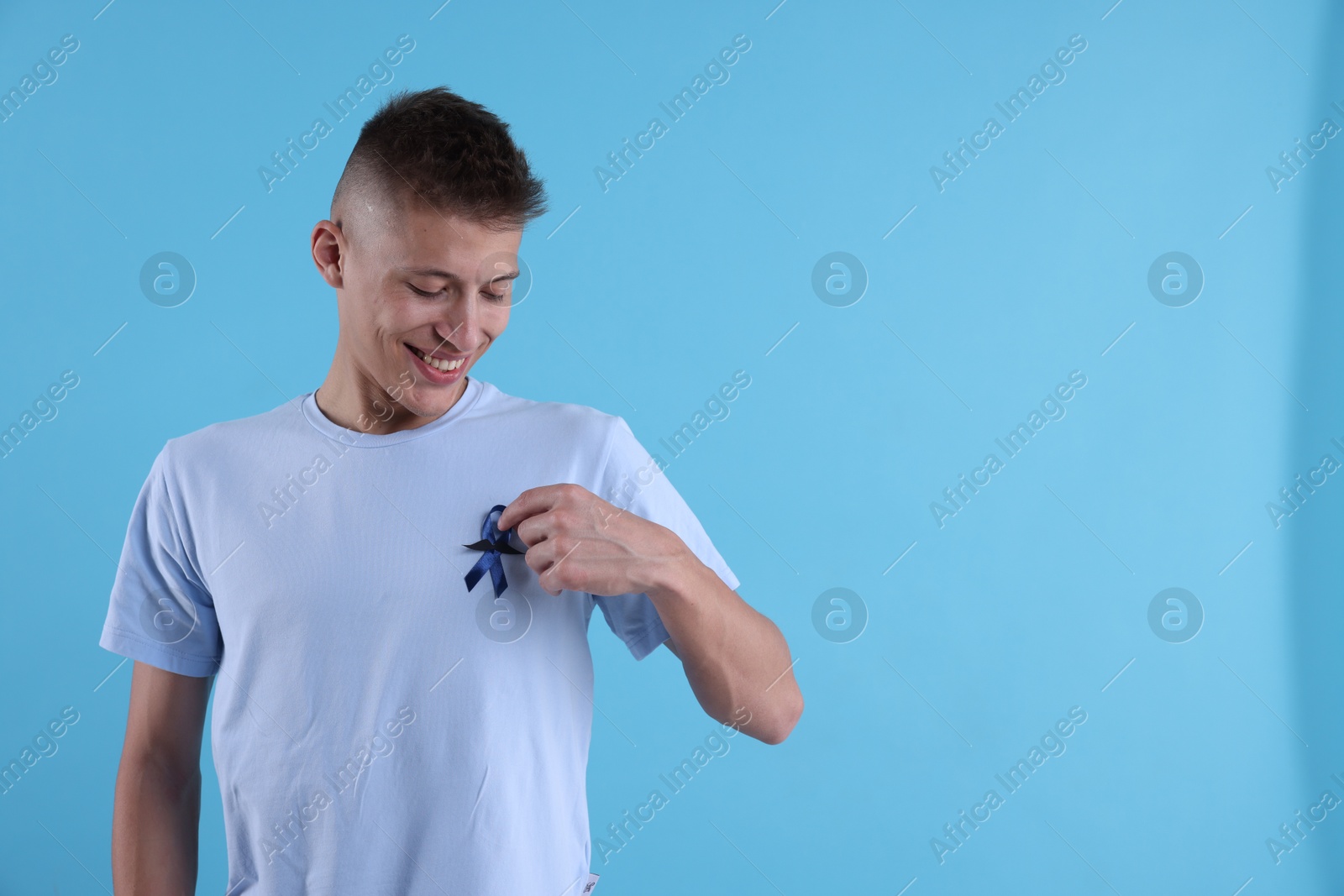 Photo of Prostate cancer awareness. Man with blue ribbon and fake mustache on color background. Space for text