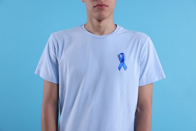 Photo of Prostate cancer awareness. Man with light blue ribbon as symbol of support on color background, closeup