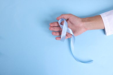 Photo of Prostate cancer awareness. Man with light blue ribbon as symbol of support on color background, top view. Space for text