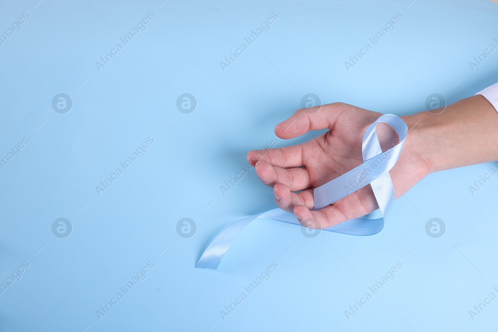 Photo of Prostate cancer awareness. Man with light blue ribbon as symbol of support on color background