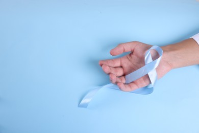 Photo of Prostate cancer awareness. Man with light blue ribbon as symbol of support on color background