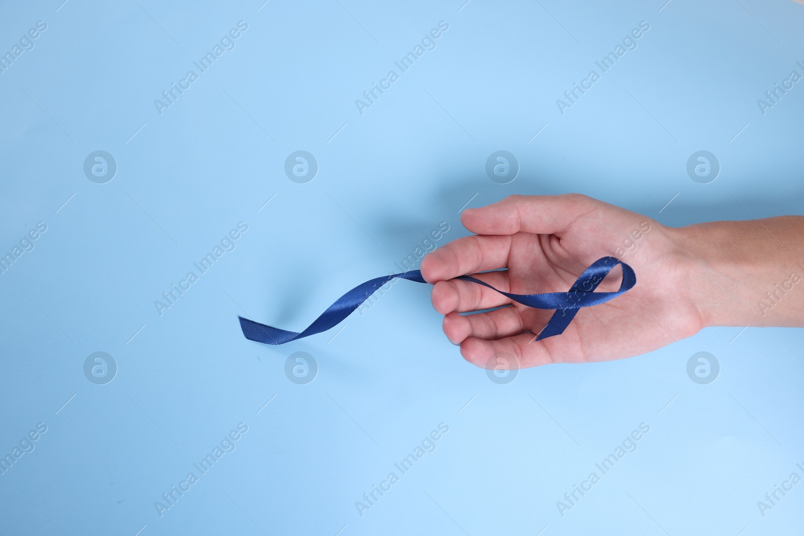 Photo of Prostate cancer awareness. Man with light blue ribbon as symbol of support on color background, top view