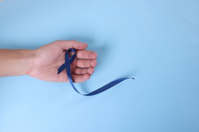 Photo of Prostate cancer awareness. Man with light blue ribbon as symbol of support on color background, top view. Space for text