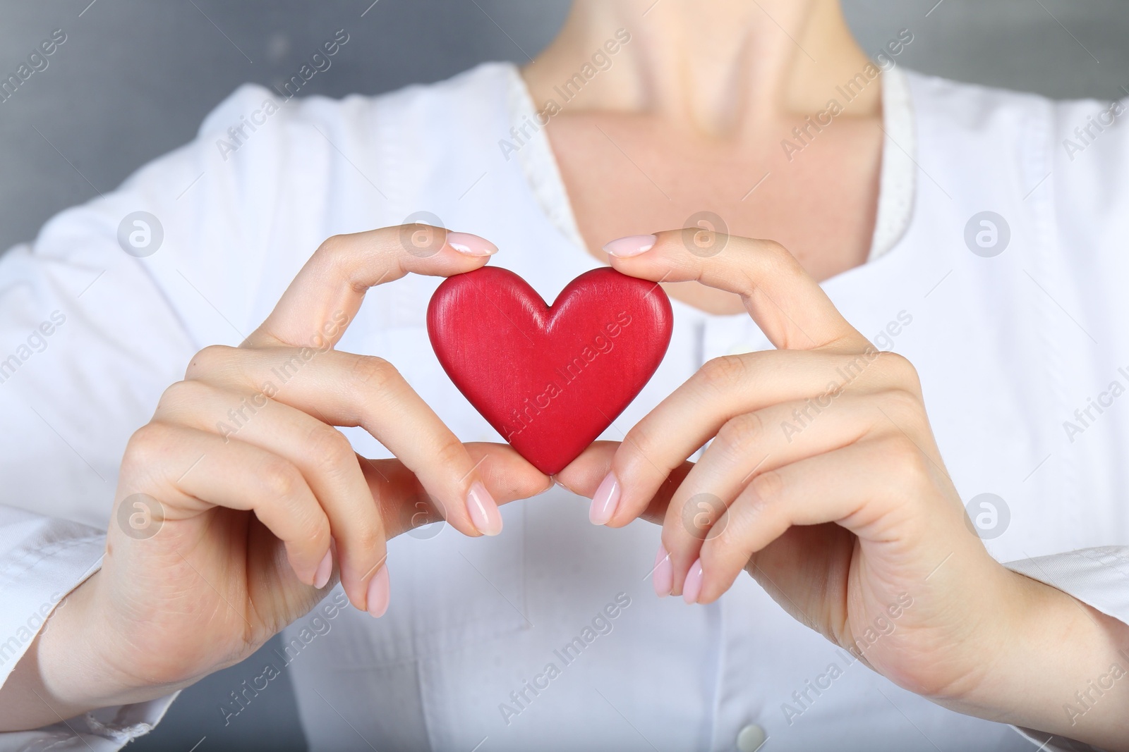 Photo of Doctor holding red heart on grey background, closeup