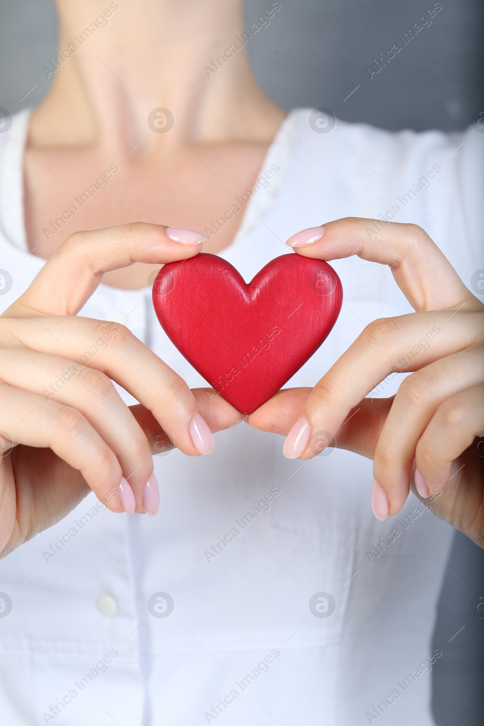 Photo of Doctor holding red heart on grey background, closeup