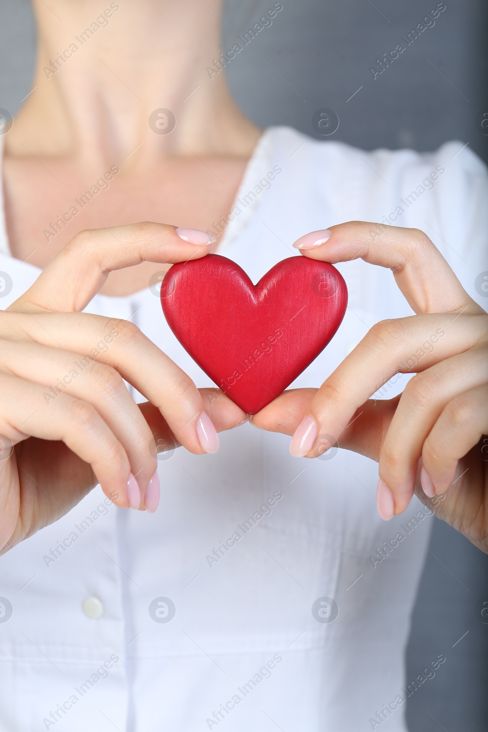 Photo of Doctor holding red heart on grey background, closeup