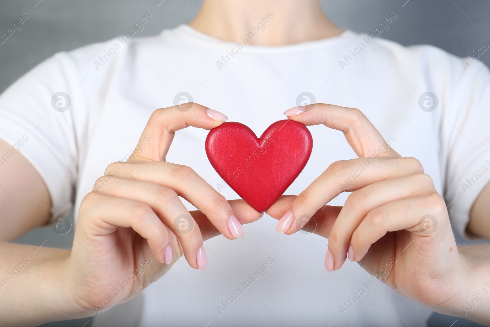 Photo of Woman holding red heart on grey background, closeup