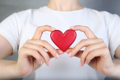 Photo of Woman holding red heart on grey background, closeup