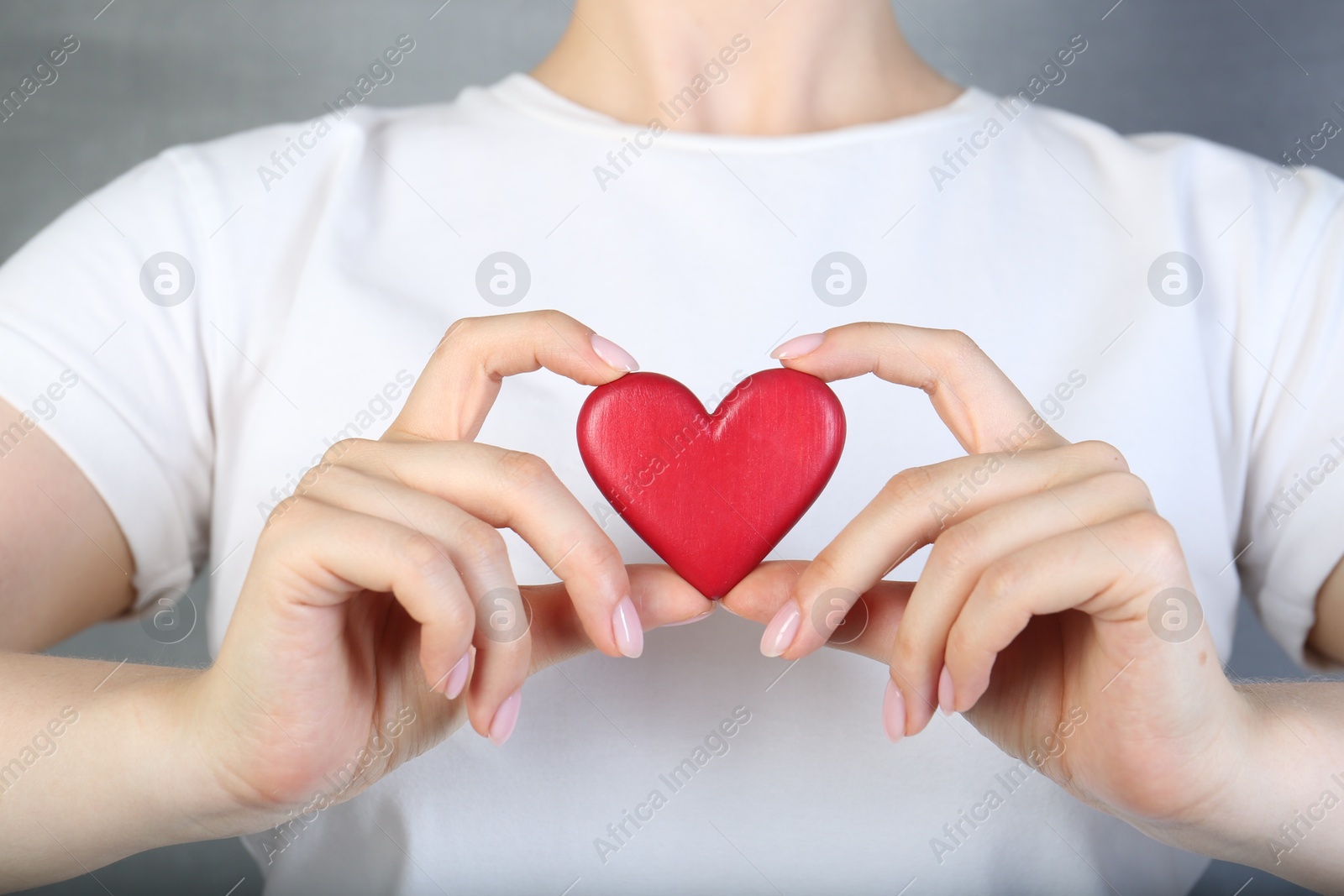 Photo of Woman holding red heart on grey background, closeup