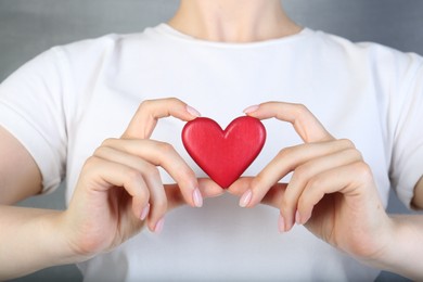 Photo of Woman holding red heart on grey background, closeup