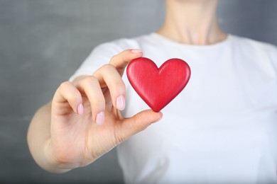 Photo of Woman holding red heart on grey background, closeup