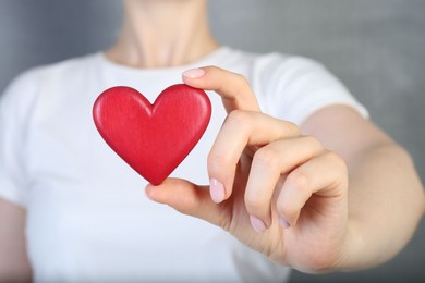 Photo of Woman holding red heart on grey background, closeup