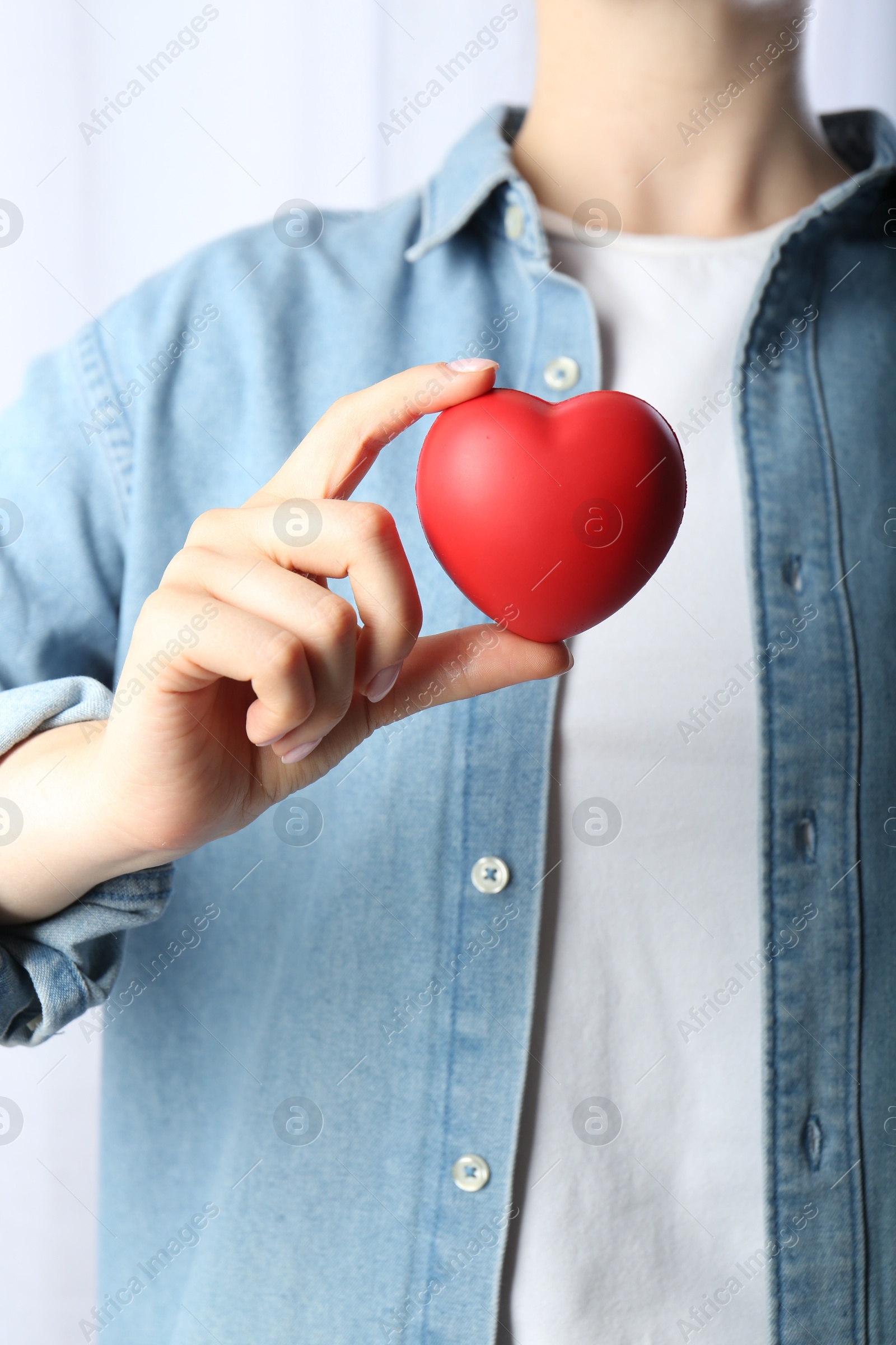 Photo of Woman holding red heart on light background, closeup